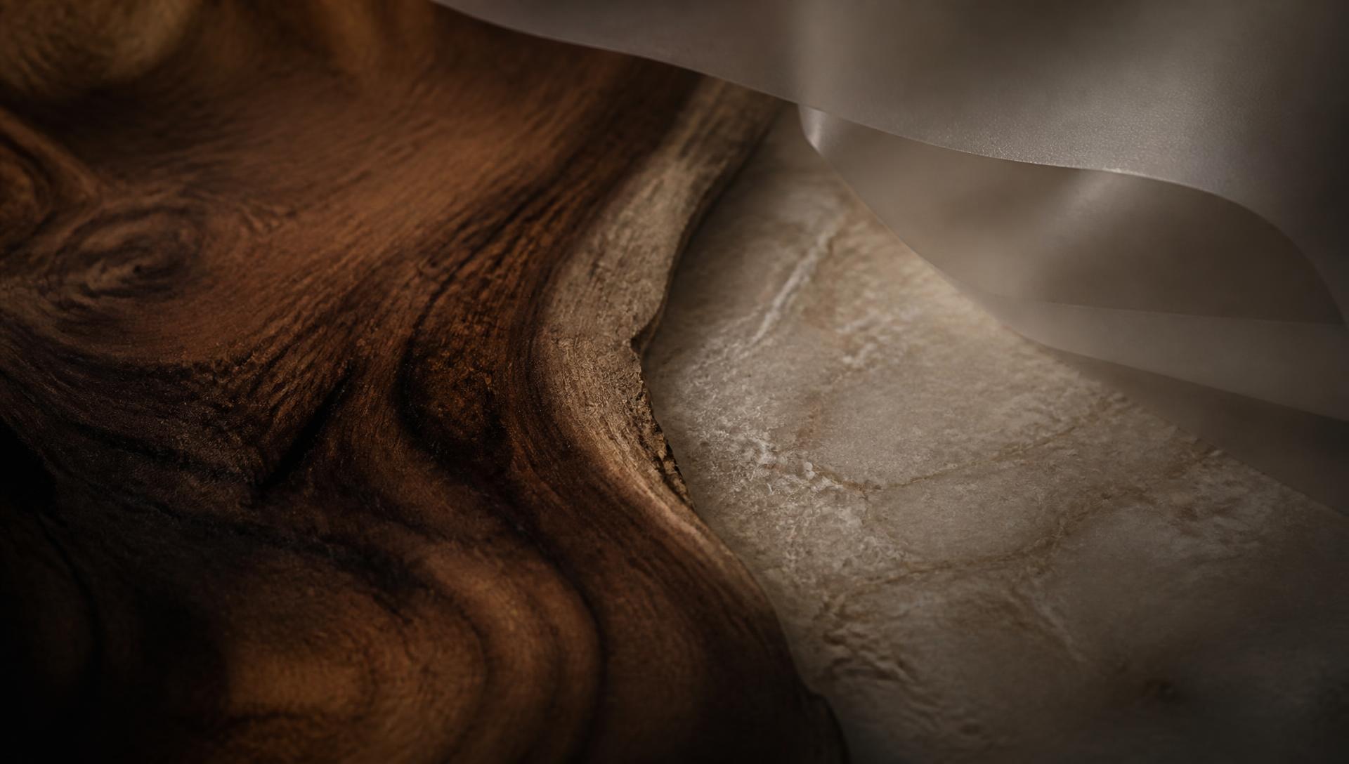 Cinematic macro of walnut grain meeting pale stone beneath a sheet of translucent film